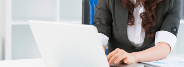 Businesswoman working on a laptop with financial documents on the desk